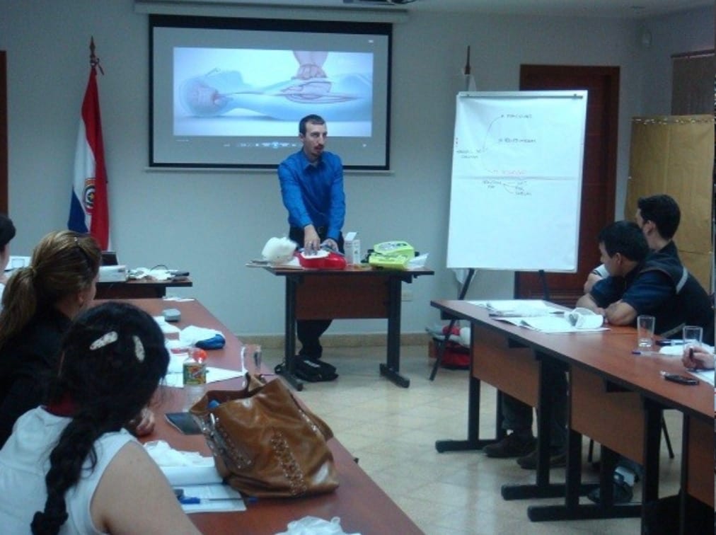An instructor teaching a hands-on CPR and AED class to a room of students