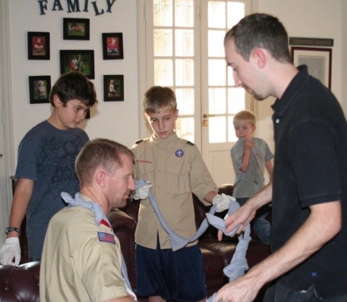Boy Scouts learning to make an arm sling with an instructor