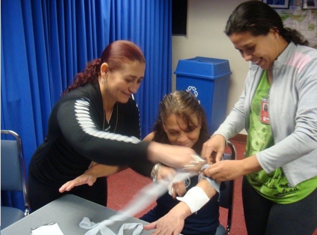 Students laughing together while they practice bandaging an arm
